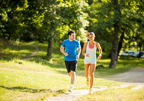 Un couple qui font un footing au soleil dans un parc